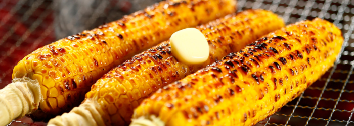 three corn cobs on the grill with butter